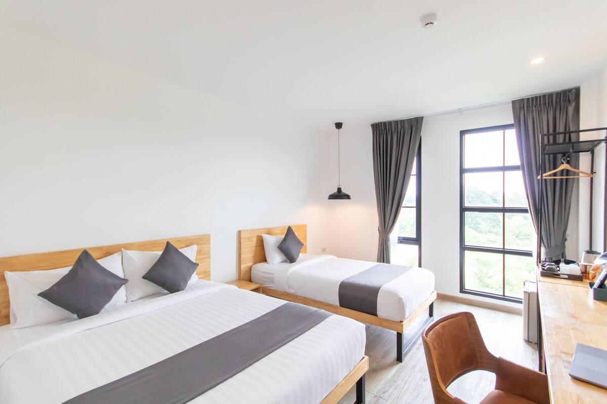 A hotel room with two beds, a desk, and a chair.