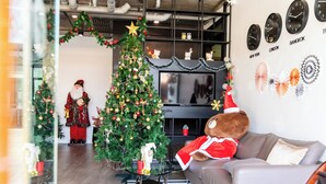 Uma sala de estar com uma árvore de Natal, um sofá, uma televisão e um urso de pelúcia.