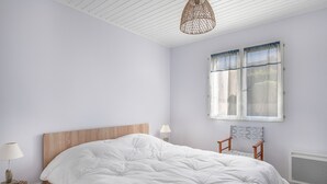 Una camera da letto con un letto grande, una testiera in legno, un comodino con una lampada, una sedia e una finestra con tende.