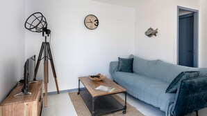 Un soggiorno moderno con un tavolino in legno, un divano blu, una sveglia a parete e un treppiede.