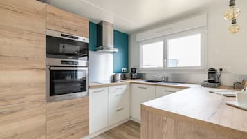 Eine moderne Küche mit Holzausstattung, Edelstahlgeräten, einem großen Fenster und einer Deckenleuchte.