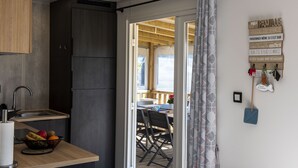 Una cucina compatta con un piano di lavoro in legno, un lavandino e un frigorifero. Si vede anche un'area pranzo con tavolo e sedie.