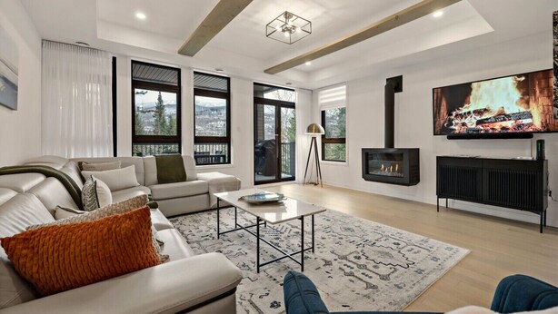 A modern living room with a fireplace, large windows, and a television. - Tremblant Prestige - Verbier 1-103 (Mont-Tremblant)