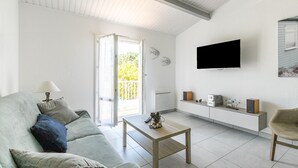 Una sala de estar moderna con un sofá, una mesa de centro y un televisor de pantalla plana montado en la pared.