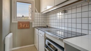 A compact kitchen with white cabinets, a tiled backsplash, a window with a view, and a built-in oven. - Superb sea view - Holidays for 5 people in Arzon (Arzon)