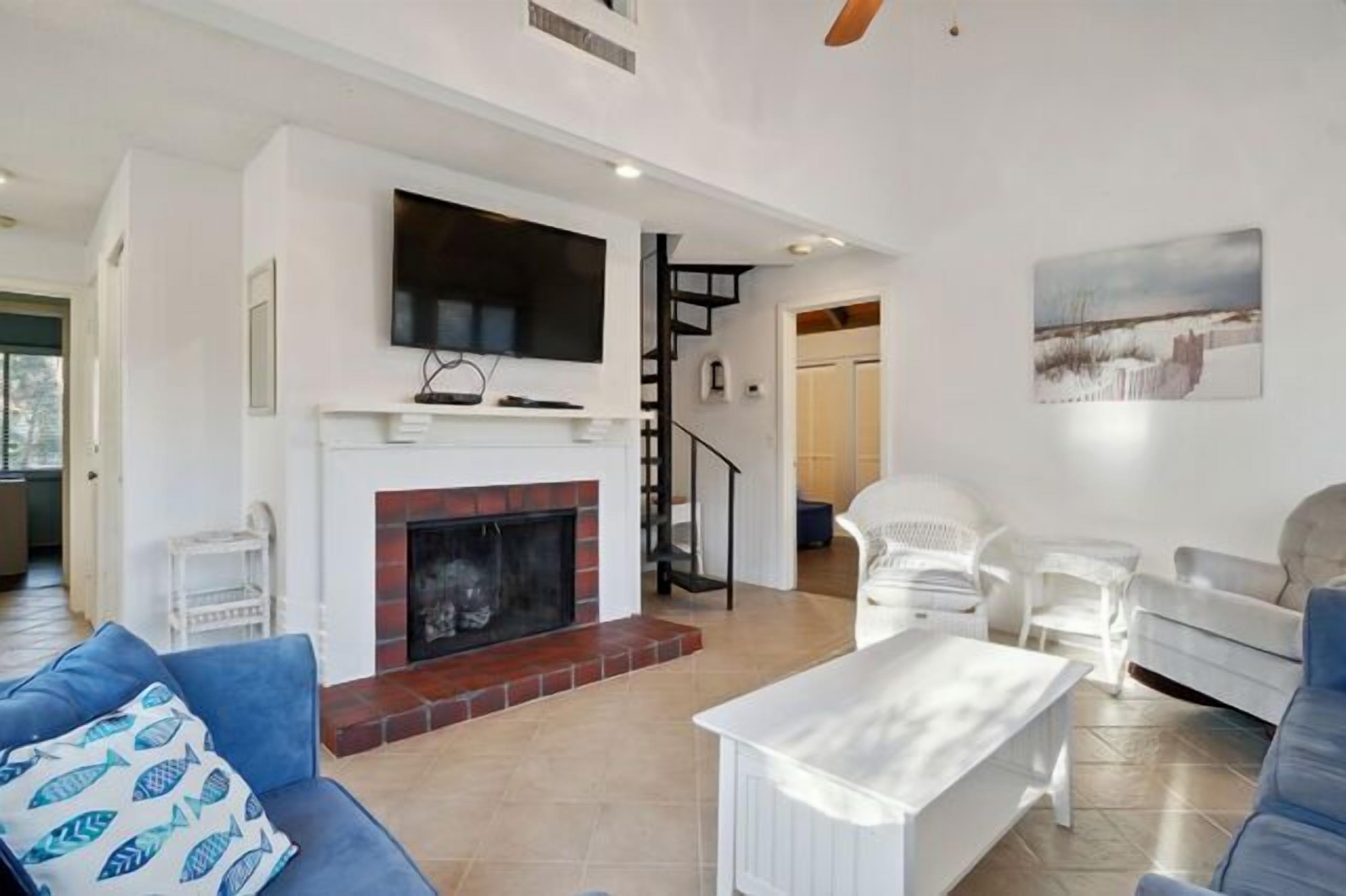 Ein modernes Wohnzimmer mit Kamin, weißen Möbeln und einer Treppe zu einer weiteren Ebene.