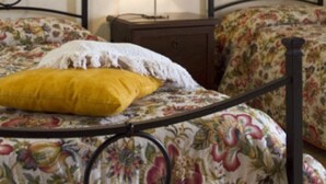 A bed with a floral bedspread, a yellow pillow, and a nightstand with a lamp.