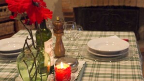 A dining table set with plates, glasses, a candle, and a salt shaker.