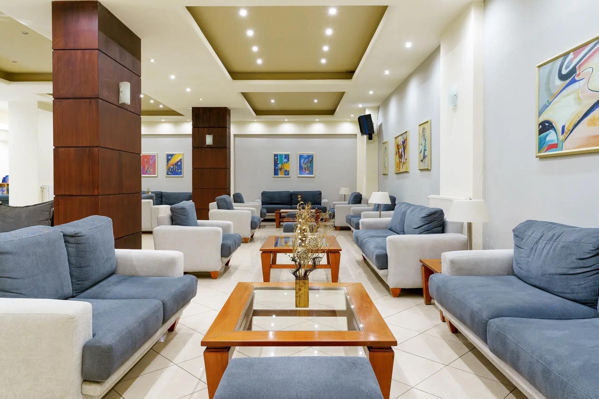 A spacious lobby with multiple seating areas, a central coffee table, and artwork on the walls.