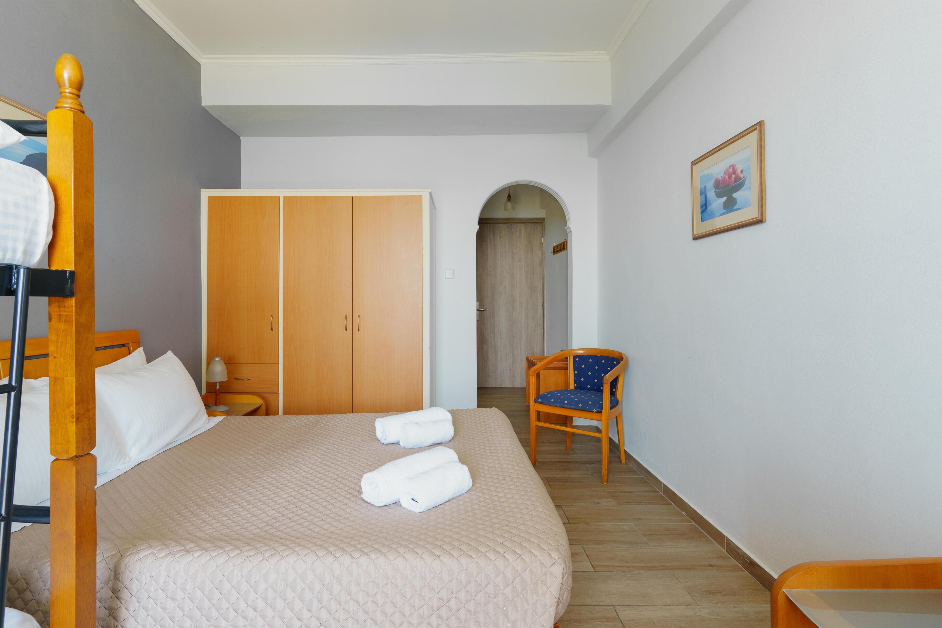 Una camera da letto con un letto, un armadio, una sedia e un quadro appeso al muro.