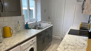 A compact kitchen with a washing machine, a sink, and a countertop. - New Day Properties-Seaside House-next to beach (South Shields)