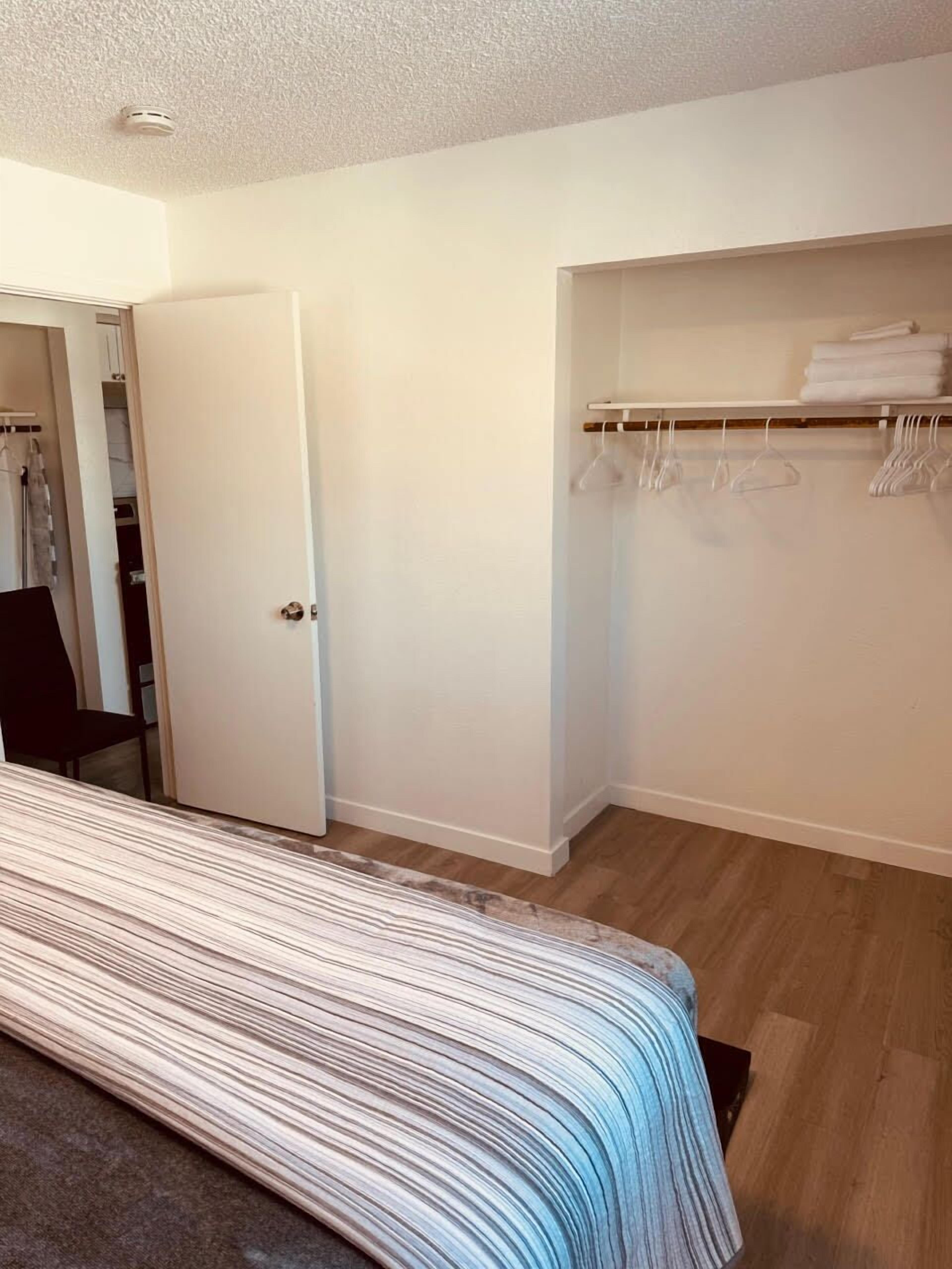 A bedroom with a bed, a closet, and a door leading to another room.