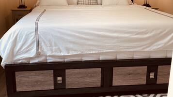 A neatly made bed with a headboard, two bedside lamps, and a geometric patterned rug.