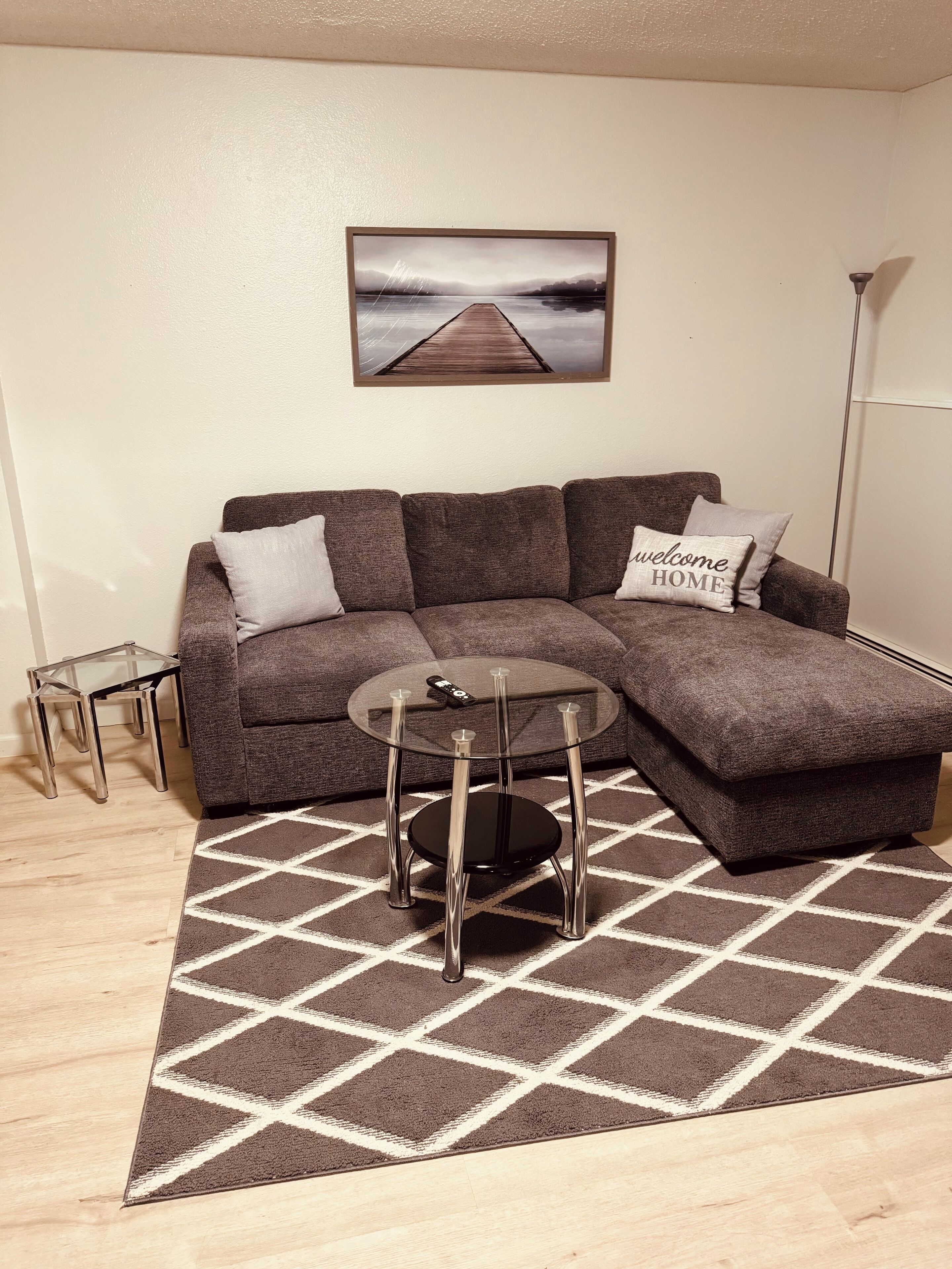 Una sala de estar moderna con un sofá modular, una mesa de centro de vidrio y una alfombra de estampado geométrico.