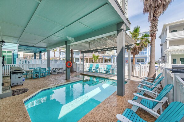 A pool area with a clear blue pool, lounge chairs, and a lifebuoy.