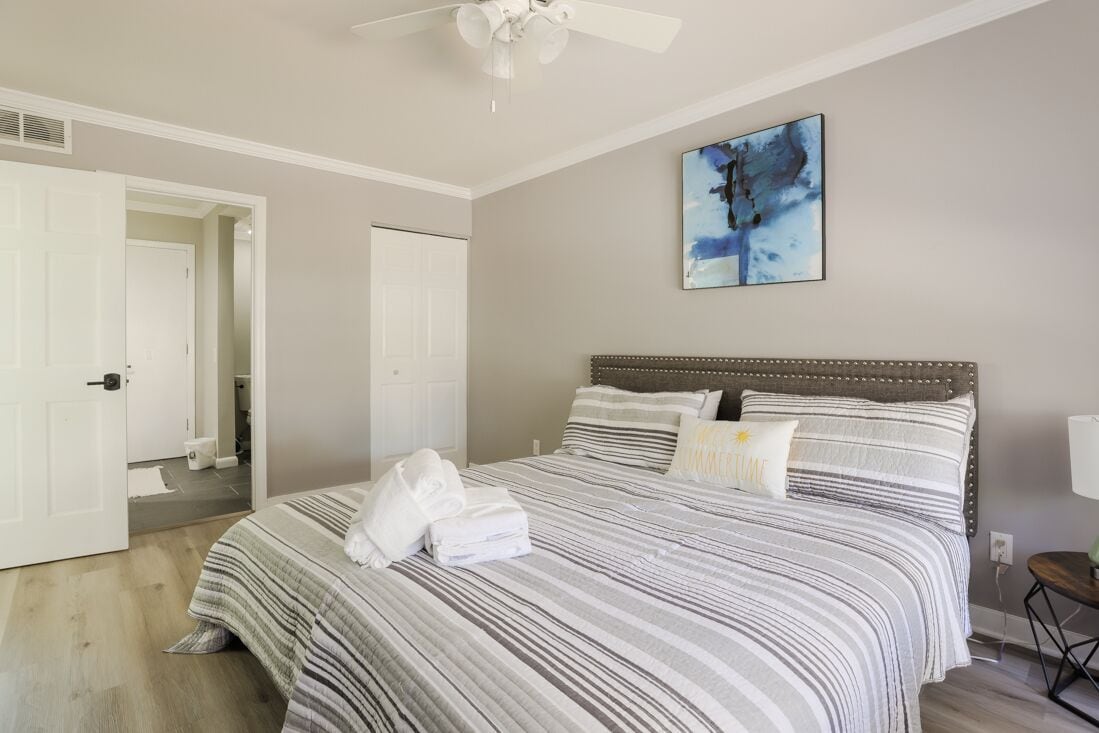 Una camera da letto con un letto grande, una ventola a soffitto e un quadro appeso al muro.