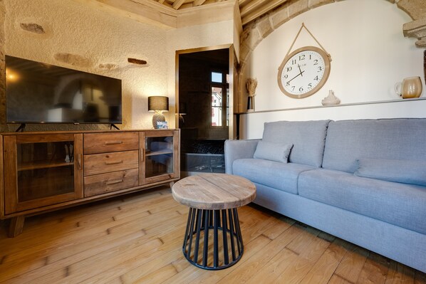 Un salon avec un téléviseur à écran plat, un meuble en bois, une table ronde en bois et un canapé bleu clair.