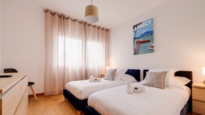 A hotel room with two beds, a desk, and a large window with curtains. - Le 305 - T3 with garage and beautiful terrace (Annecy)