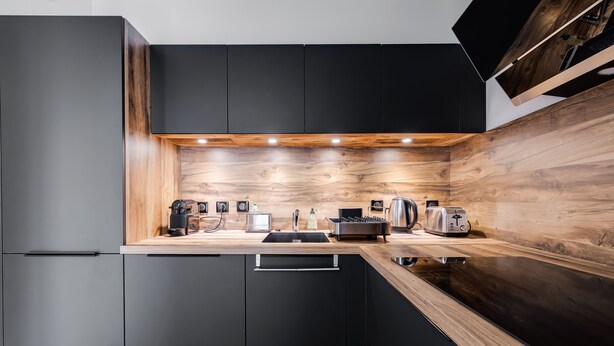 A modern kitchen with black cabinets, wooden countertops, and built-in appliances. - Le 305 - T3 with garage and beautiful terrace (Annecy)
