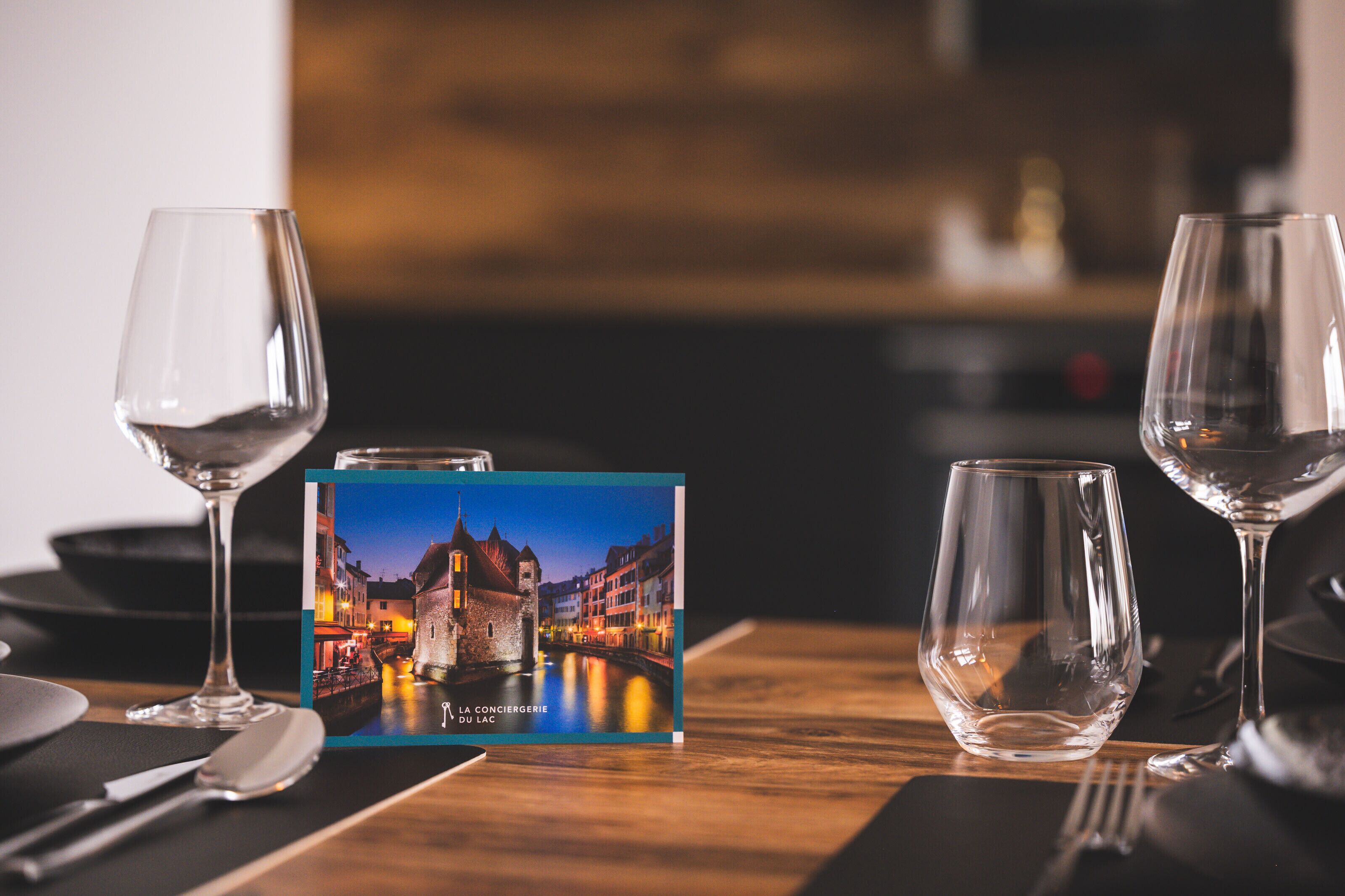 A table set with wine glasses, a menu, and a postcard of a castle.