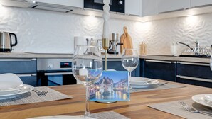 Una cocina moderna con armarios blancos, un microondas y un comedor dispuesto con platos, vasos y un mantel individual con una imagen panorámica.