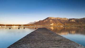 A wooden pier extending into calm water with a mountain in the background.