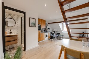 A modern kitchen with wooden cabinets, a built-in washing machine, and a dining area with a table and chairs. - Duplex Vue Montagne - ideally located with its view (Annecy)