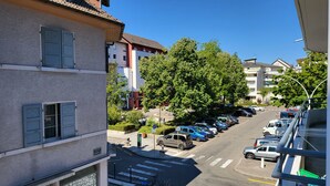 Une vue de rue avec des voitures garées, un passage piéton et des immeubles dotés de balcons.