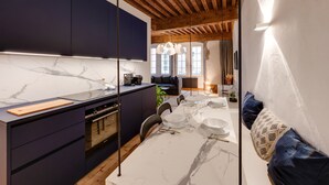 A modern kitchen with dark cabinets, a marble countertop, and a dining area with a white table set for four. - L'Appart' - Ideal for a stay in the city center, near the Lake (Annecy)