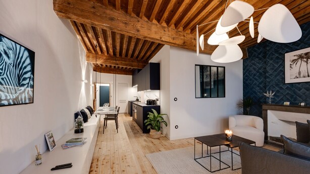 A modern living room with wooden flooring, a dining area, and a kitchen with dark cabinetry. - L'Appart' - Ideal for a stay in the city center, near the Lake (Annecy)