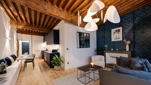 A modern living room with a wooden ceiling, a dining area, and a cozy seating area with a fireplace. - L'Appart' - Ideal for a stay in the city center, near the Lake (Annecy)
