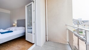 Habitación de hotel con cama, puerta corrediza al balcón y vista de la ciudad.