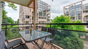 A balcony with a glass table and chairs, overlooking a garden and adjacent buildings. - The Parc des Raisses - T2 for 4 people (Annecy)