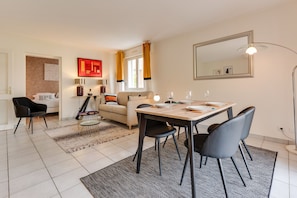 Una sala moderna con un sofá, una mesa de comedor con sillas, una mesa auxiliar y una lámpara.