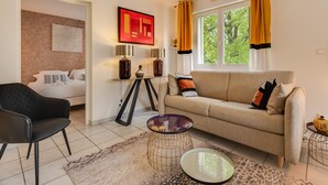 A living room with a sofa, a chair, a coffee table, and a painting on the wall. - The Parc des Raisses - T2 for 4 people (Annecy)