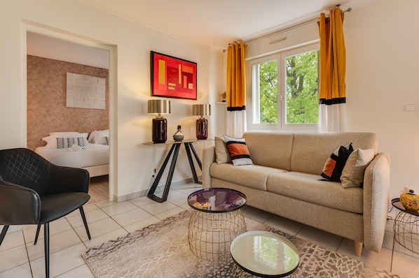 Una sala de estar con un sofá, una silla, una mesa de centro y un cuadro en la pared.