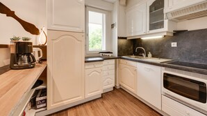 A modern kitchen with white cabinetry, a built-in oven, and a window providing natural light. - The Parc des Raisses - T2 for 4 people (Annecy)