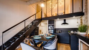 Une cuisine moderne dotée d’un îlot central, de meubles de rangement noirs et d’un escalier menant à un niveau supérieur.