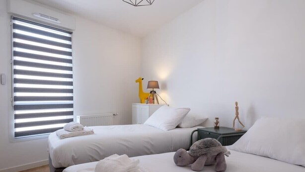 Ein Hotelzimmer mit zwei Betten, einer Lampe, einem Stofftier und einem Heizkörper.