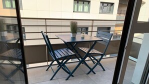 Ein Balkon mit Tisch, Stühlen, einer Topfpflanze und Blick auf ein Gebäude.