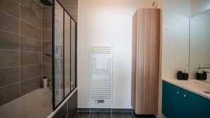 Et moderne badeværelse med bruser, håndklædetørrestativ og et træskab.