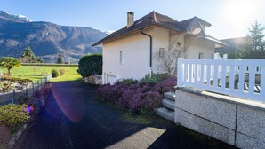 A white house with a sloped roof, a paved driveway, and a white fence. - Entre lac et montagnes (Doussard)