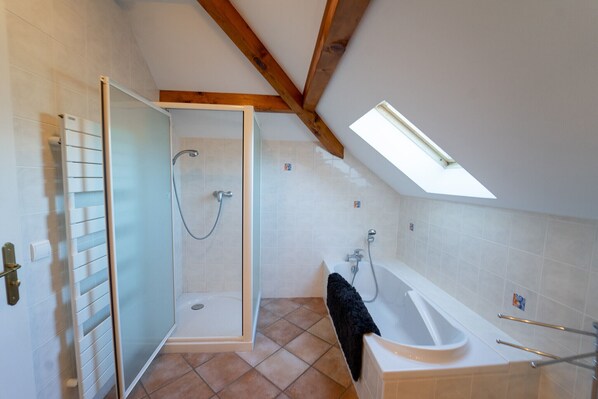 Un baño moderno con cabina de ducha de vidrio, una bañera y un tragaluz.