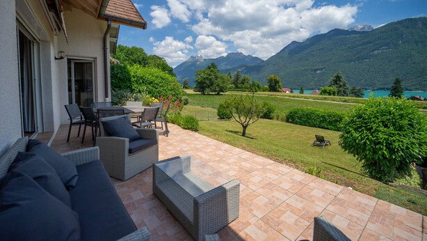 A patio with outdoor furniture, a view of mountains, and a lake. - Entre lac et montagnes (Doussard)