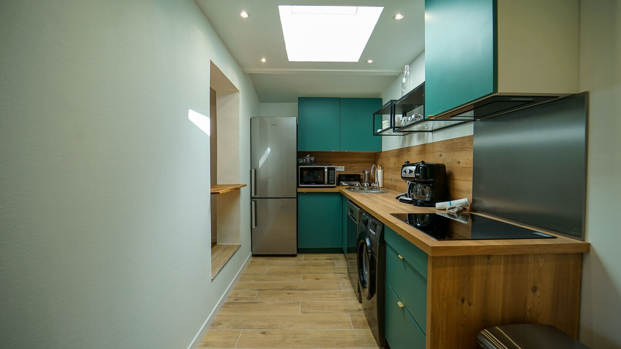 A compact kitchen with teal cabinets, a stainless steel refrigerator, a microwave, and a coffee maker.