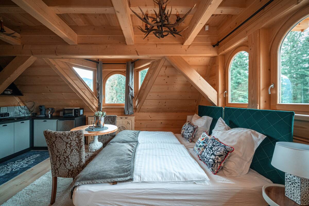 Une chambre confortable dans un chalet en bois, avec un lit, une table à manger et un coin cuisine.