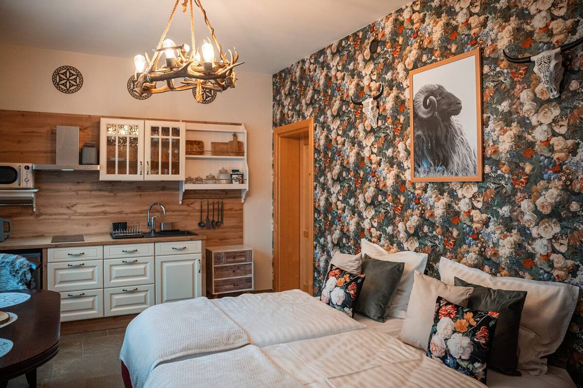 Une chambre avec un grand lit, une table de chevet et une commode. Il y a également un coin cuisine équipé d’un four à micro-ondes, d’un évier et de placards.