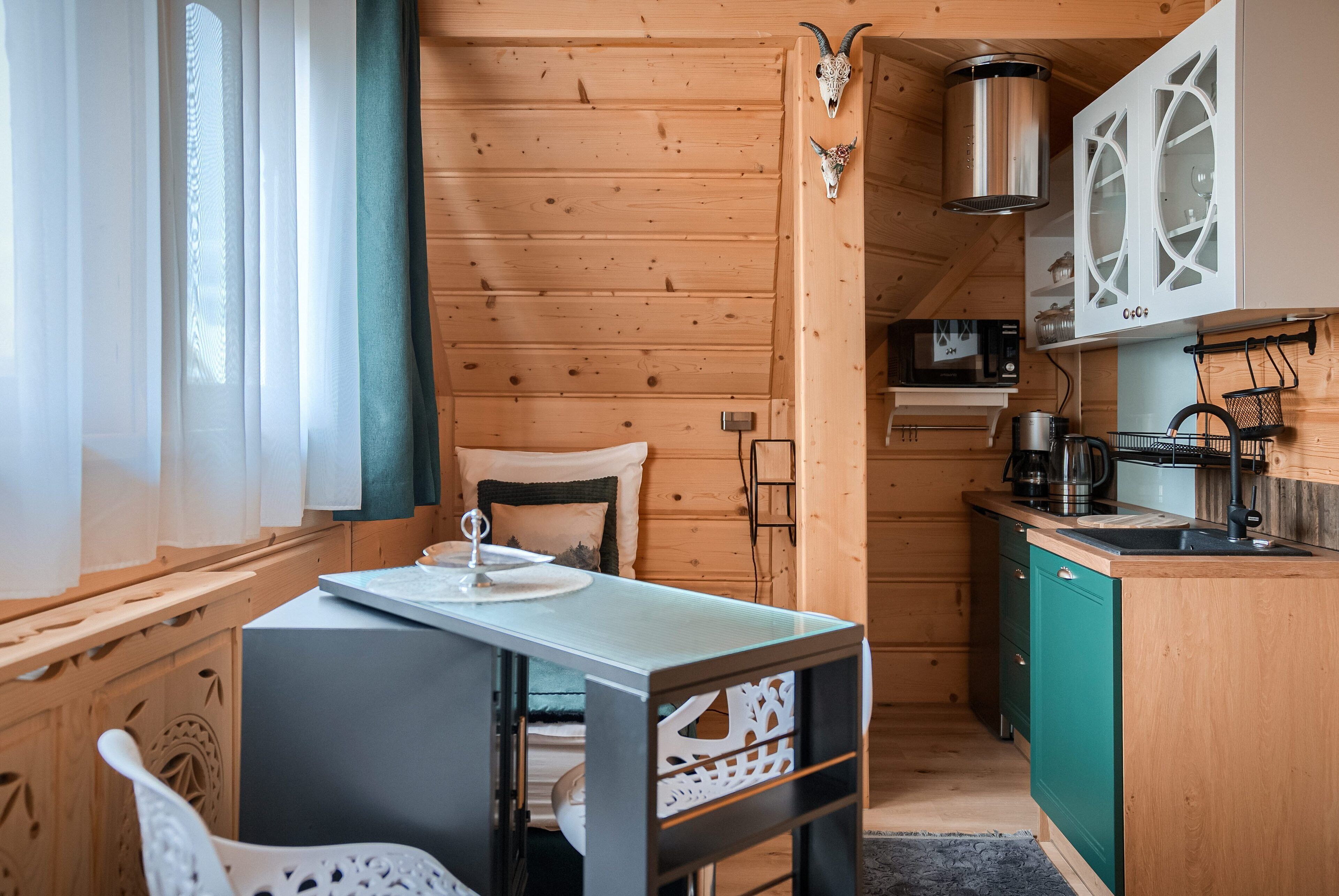 A compact kitchen with wooden walls, a small dining area, and a microwave.