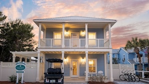 A two-story building with a balcony, a covered porch, and a sign indicating a rental service.