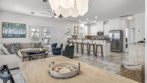 A modern kitchen with white cabinets, a stainless steel refrigerator, and a bar area with stools.